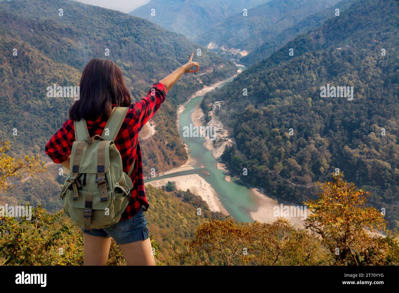 Young girl tourist enjoys a scenic aerial view of Teesta river and Himalayan landscape from Lover's Point at Darjeeling, India. Stock Photo
