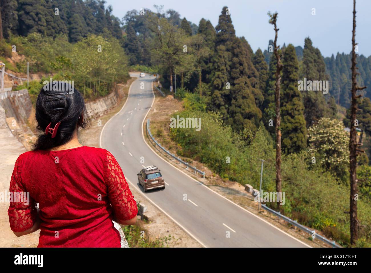 Female tourist enjoys an aerial view of mountain highway road with scenic landscape at Lava in the district of Kalimpong India Stock Photo