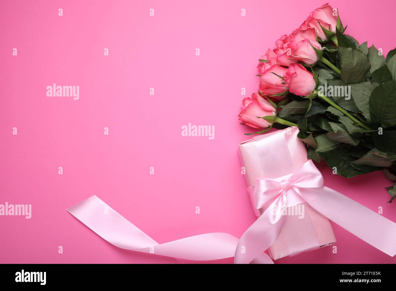 Beautiful gift box with bow and roses on pink background, flat lay ...