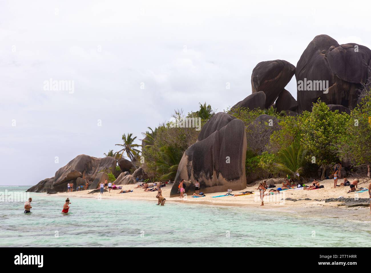 La Digue, Seychelles - August 16, 2023: Anse Union beach landscape tourists rest at the coast near black rocks Stock Photo