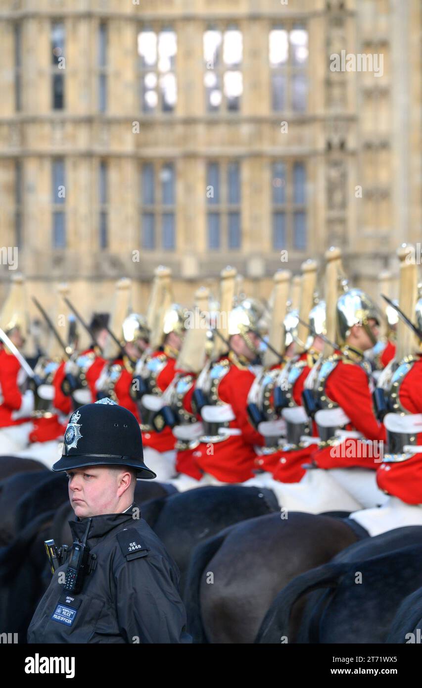 Police officer with members of the Household Cavalry waiting in Westminster during King Charles III first State Opening of Parliament as king. 7th Nov Stock Photo