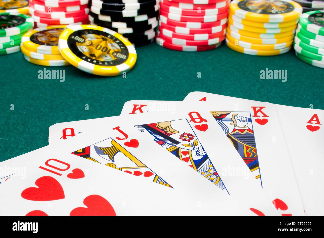royal flush and unfocused gambling chips of a green fabric background Stock Photo