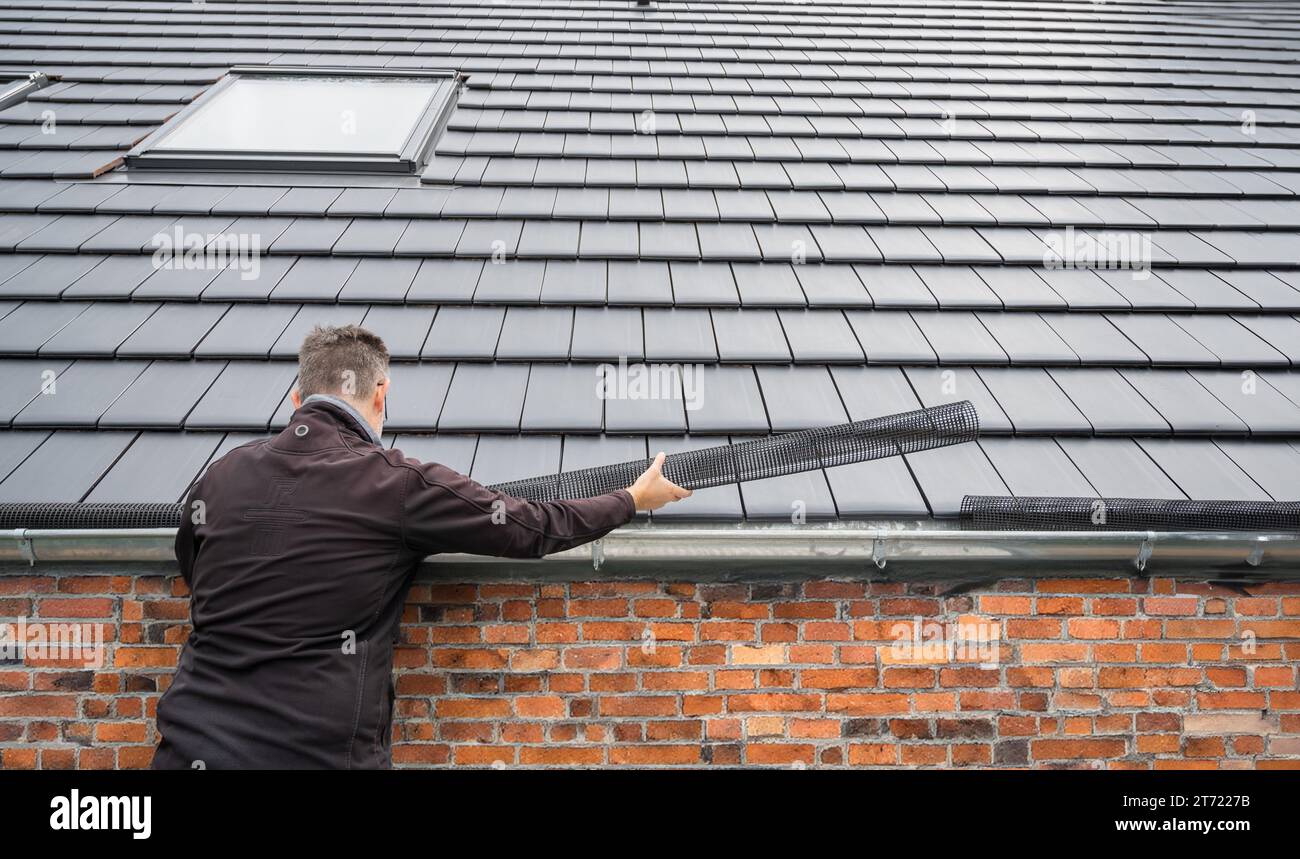 Man puts a gutter mesh to the rain gutter to protect the gutter from ...