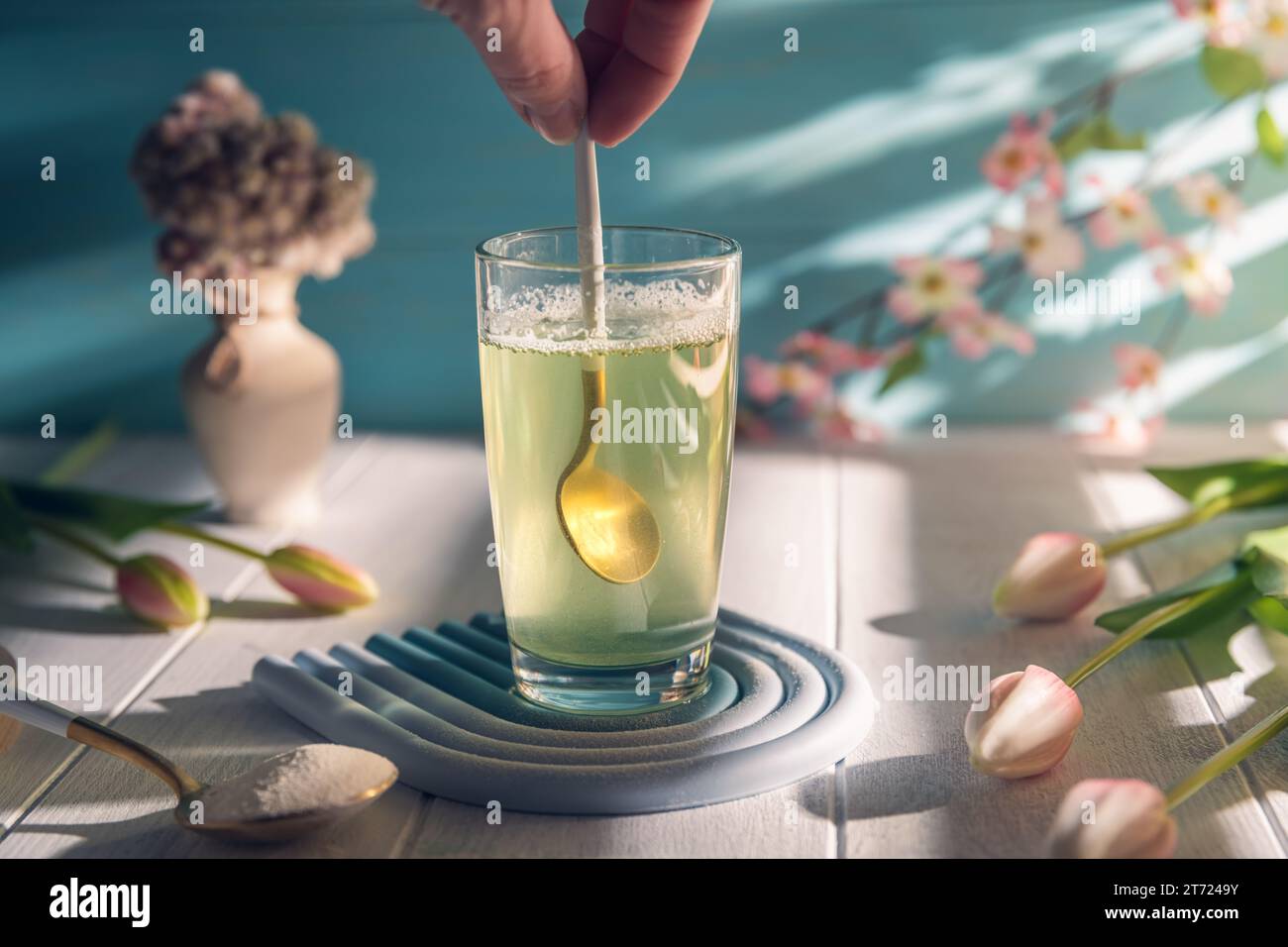 women's hand spoons collagen in a glass of water, Healthy and anti-age concept Stock Photo