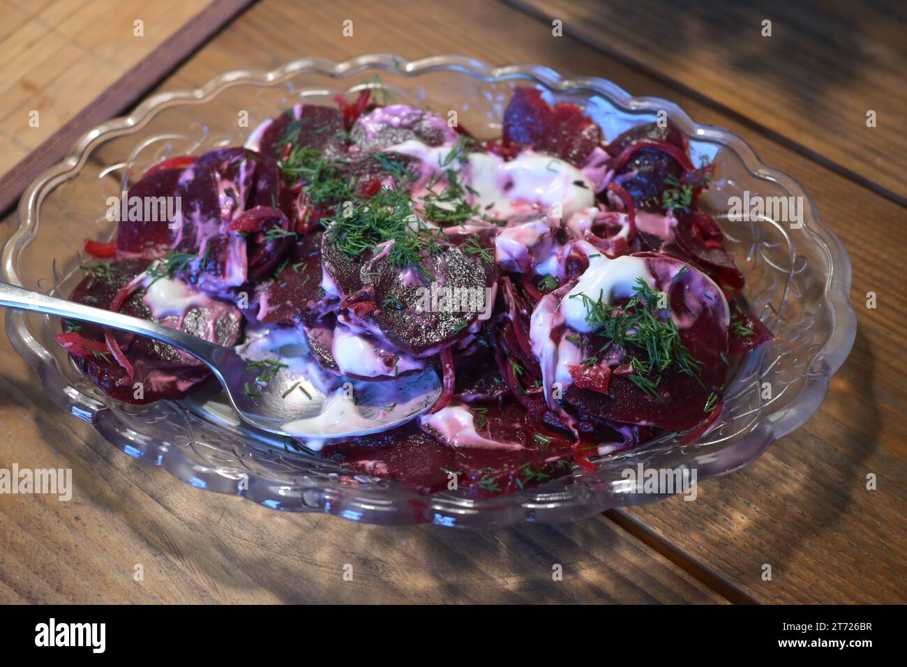 Red beet salad with a creamy dressing and dill garnish, healthy vegetarian dish in a glass bowl, selected focus, narrow depth of field Stock Photo