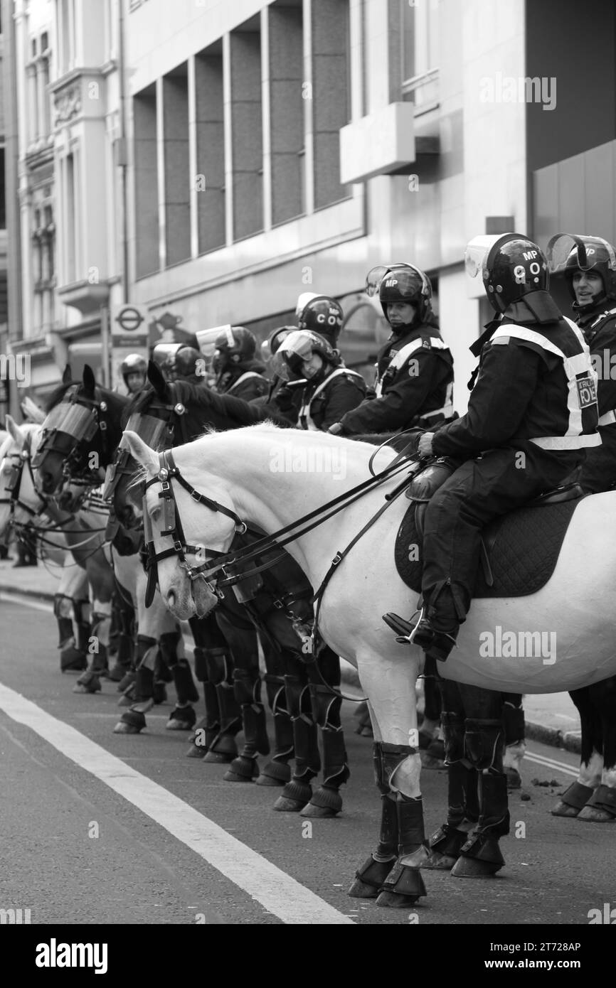 Police on duty in Central London. Black and White. Monochrome. The thin Blue line. Cops. Old Bill. Crowd control. Streets. Uniform police officers. Special divisions. Mounted. Dogs. K9. Mounted. Horses. Riot police. Law and order. Peace. Stock Photo