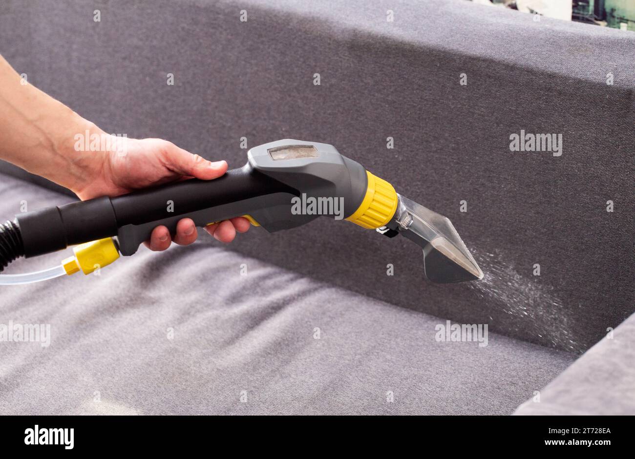 Applying a special cleaning solution to clean stains and dirt on upholstery of upholstered furniture. The first stage of dry cleaning. Stock Photo