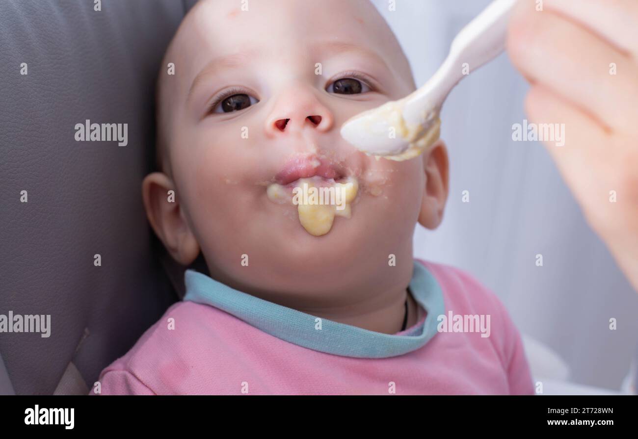 A mother feeds her child, a oneyearold boy, with millet porridge