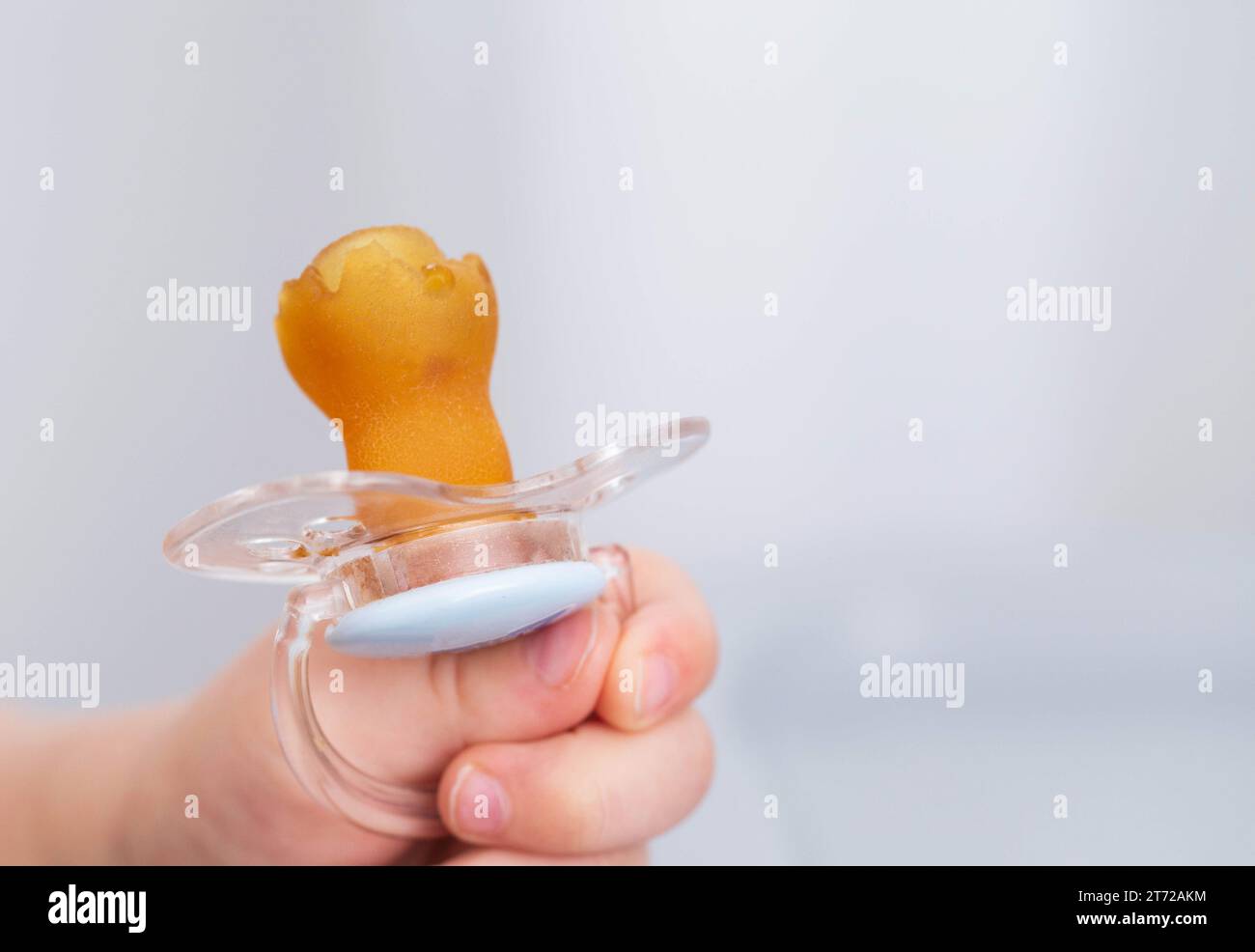 The baby is holding a torn and chewed silicone pacifier in his hands ...