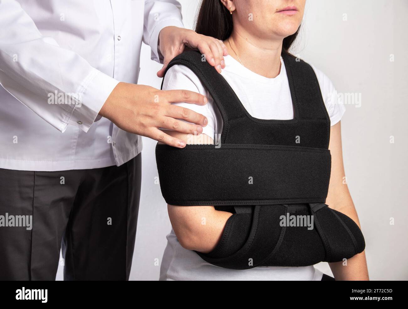 A doctor surgeon examines a girl's shoulder after surgery. Bandage on the shoulder joint during rehabilitation after surgery on the shoulder joint, te Stock Photo