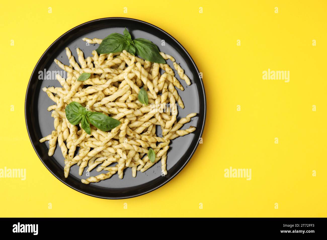 Plate of delicious trofie pasta with pesto sauce and basil leaves on