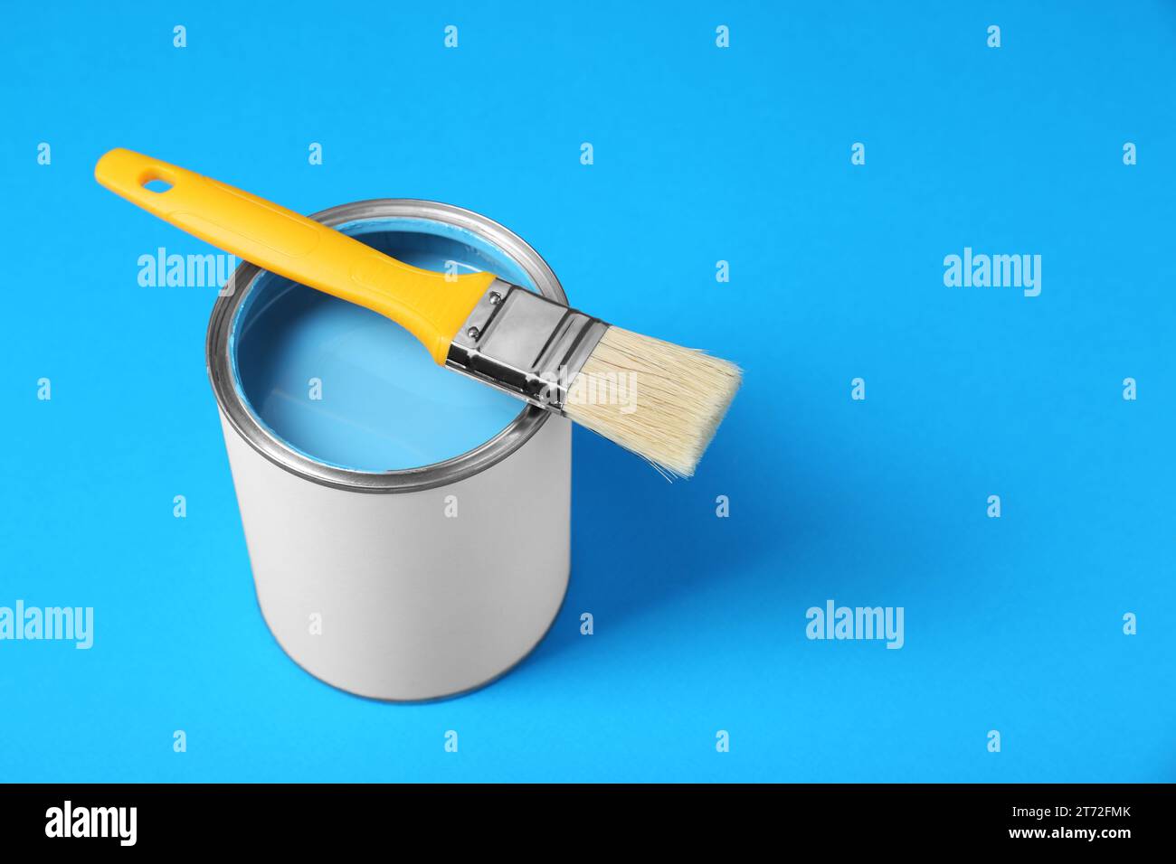 Can of paint with brush on light blue background, space for text Stock