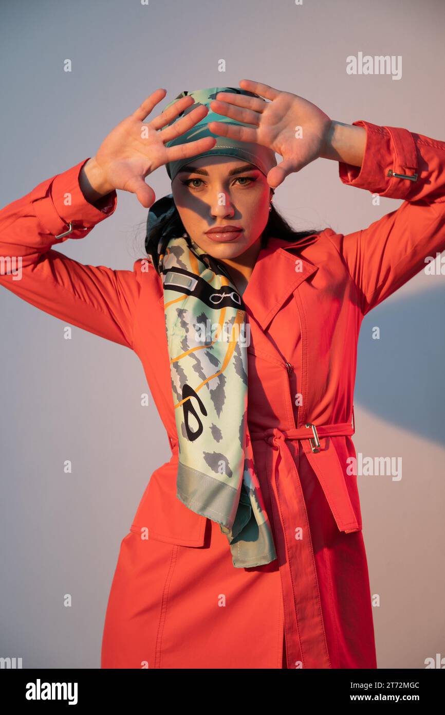 a beautiful woman in an orange dress holds her hands to her face Stock ...