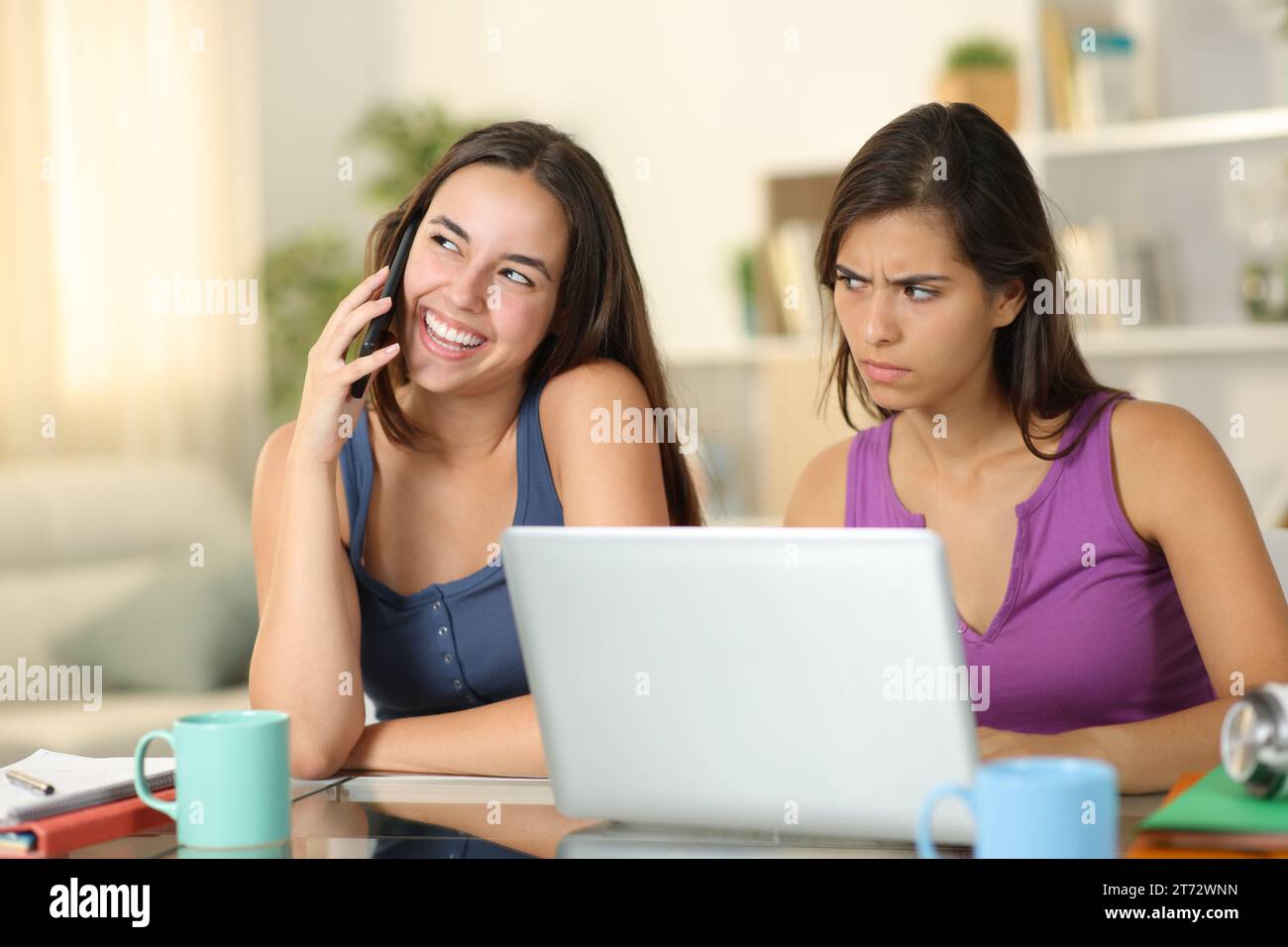 Suspicious student listening a friend talking on phone at home Stock Photo