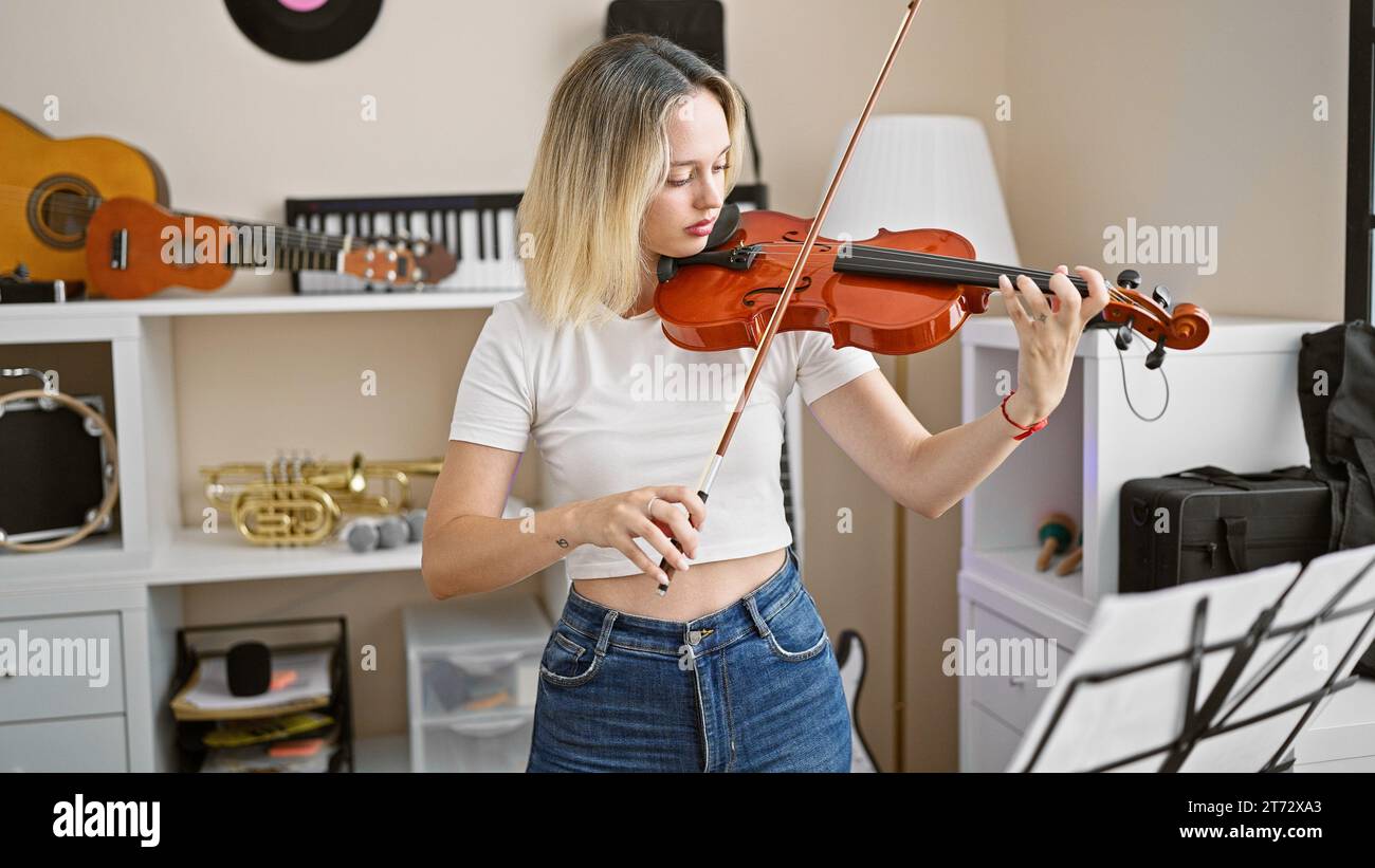 Young blonde woman musician playing violin at music studio Stock Photo ...