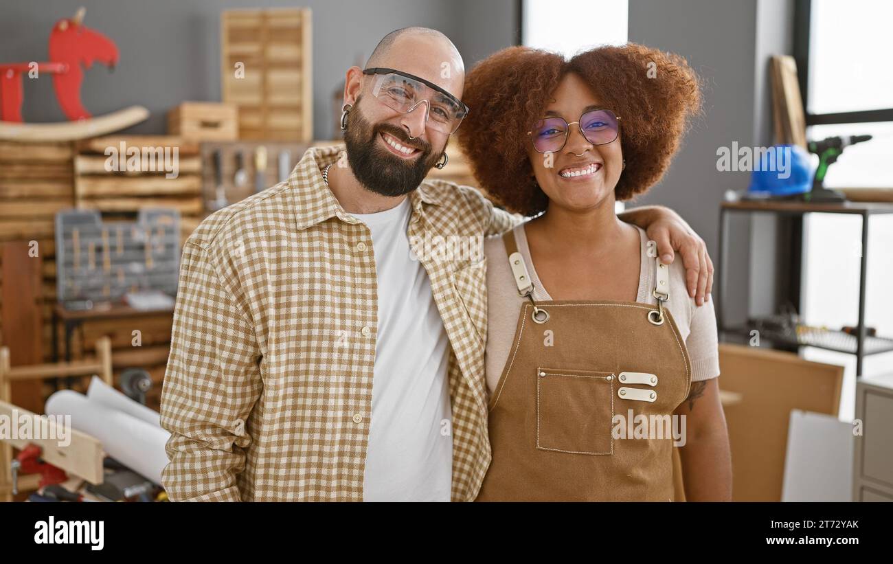 Two smiling carpenters in safety glasses, hugging amid the lumber