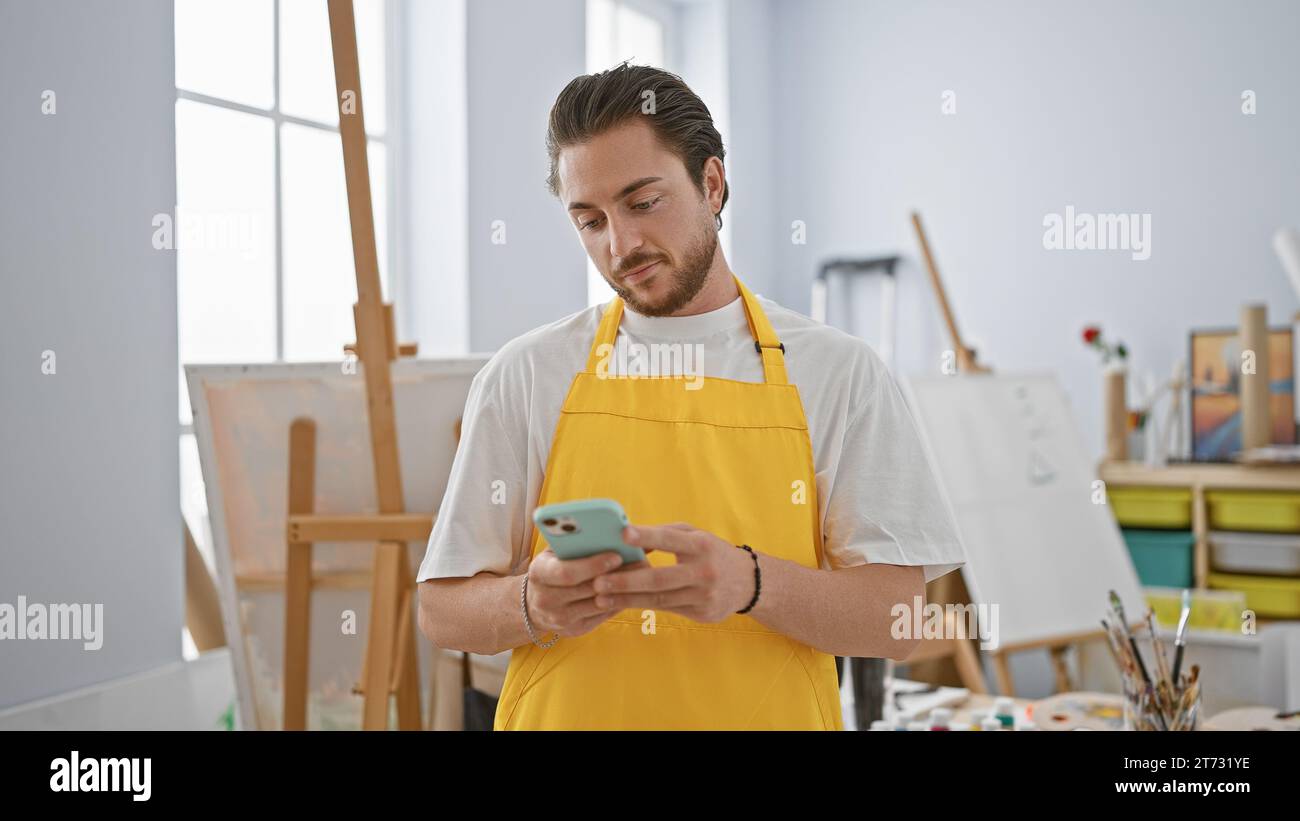 Young hispanic man artist using smartphone at art studio Stock Photo