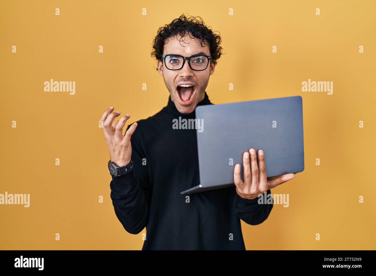 Hispanic Man Using Computer Hispanic man working using computer laptop celebrating victory with ...