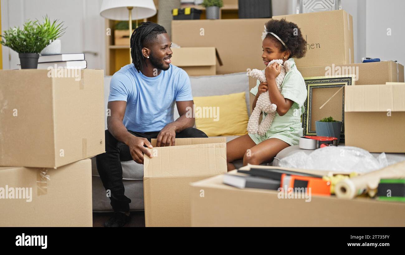 African american father and daughter unpacking teddy bear of cardboard ...