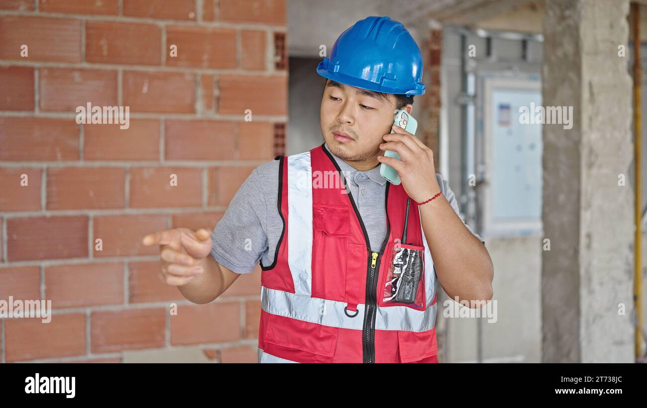 builder talking on smartphone at construction site Stock Photo
