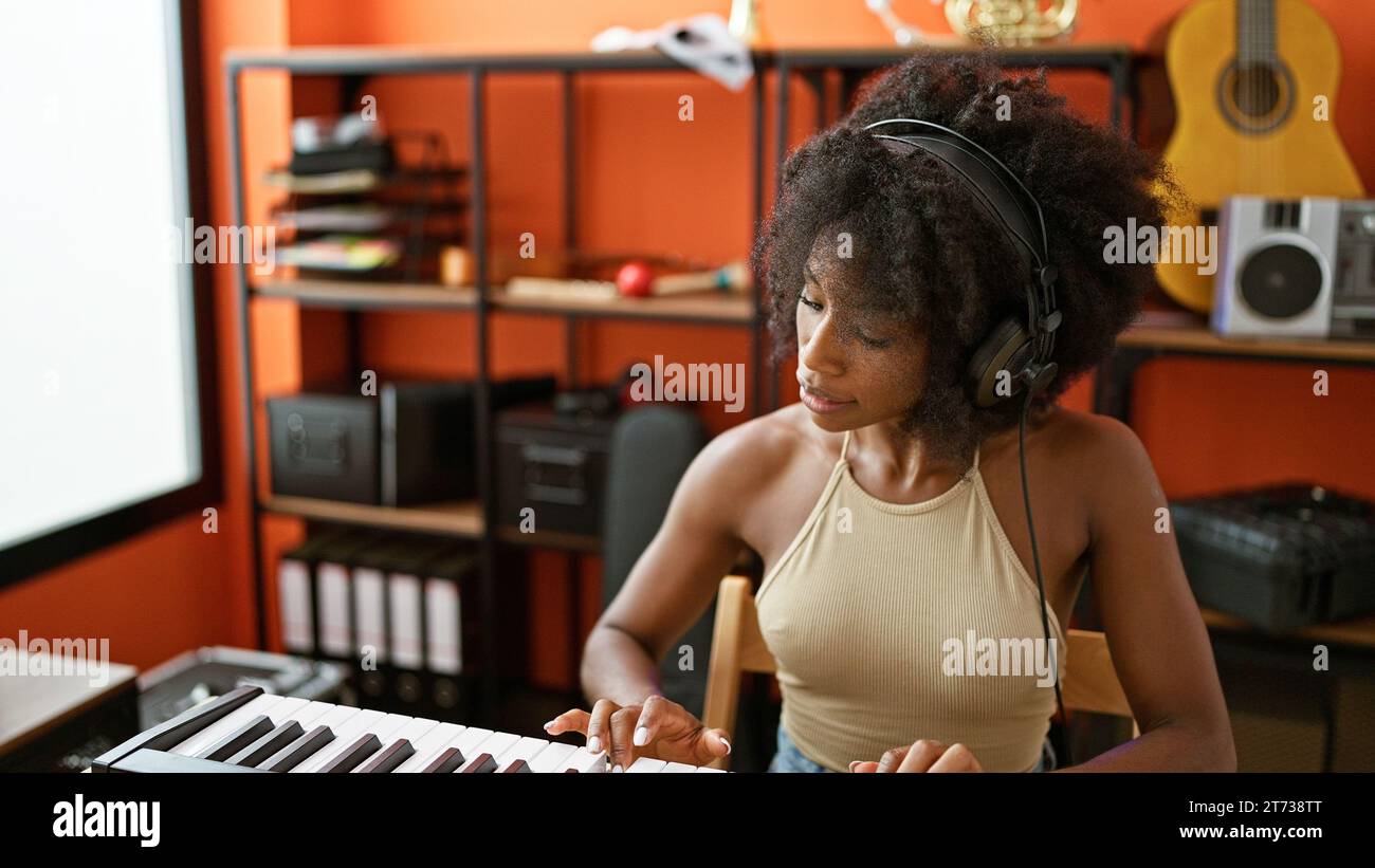 African american woman musician wearing headphones playing piano at