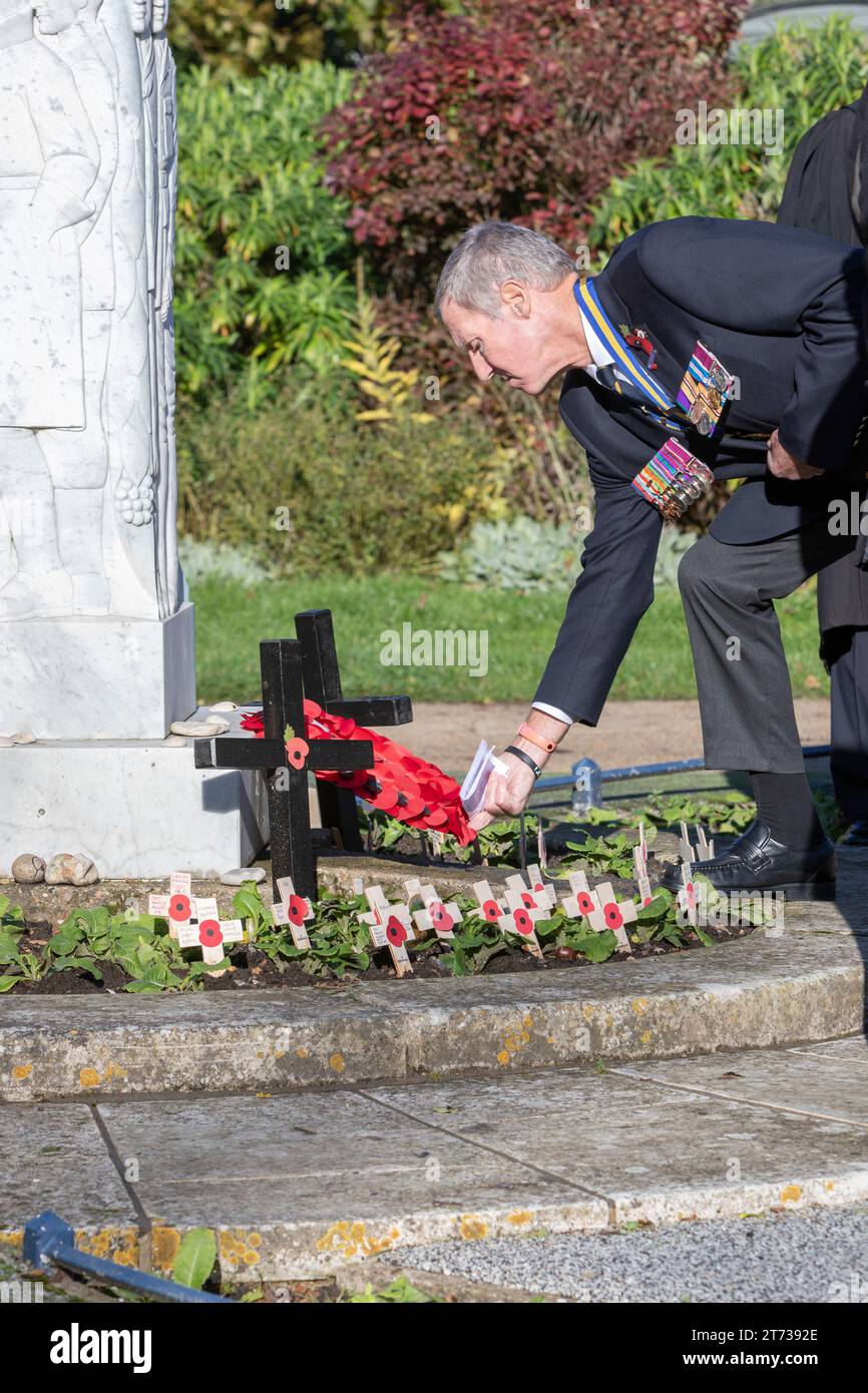 A man laying a wreath of poppies at a war memorial Stock Photo