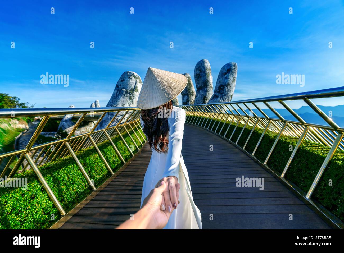 Women tourist holding man's hand and leading him to Golden bridge in Da nang, Vietnam. Stock Photo