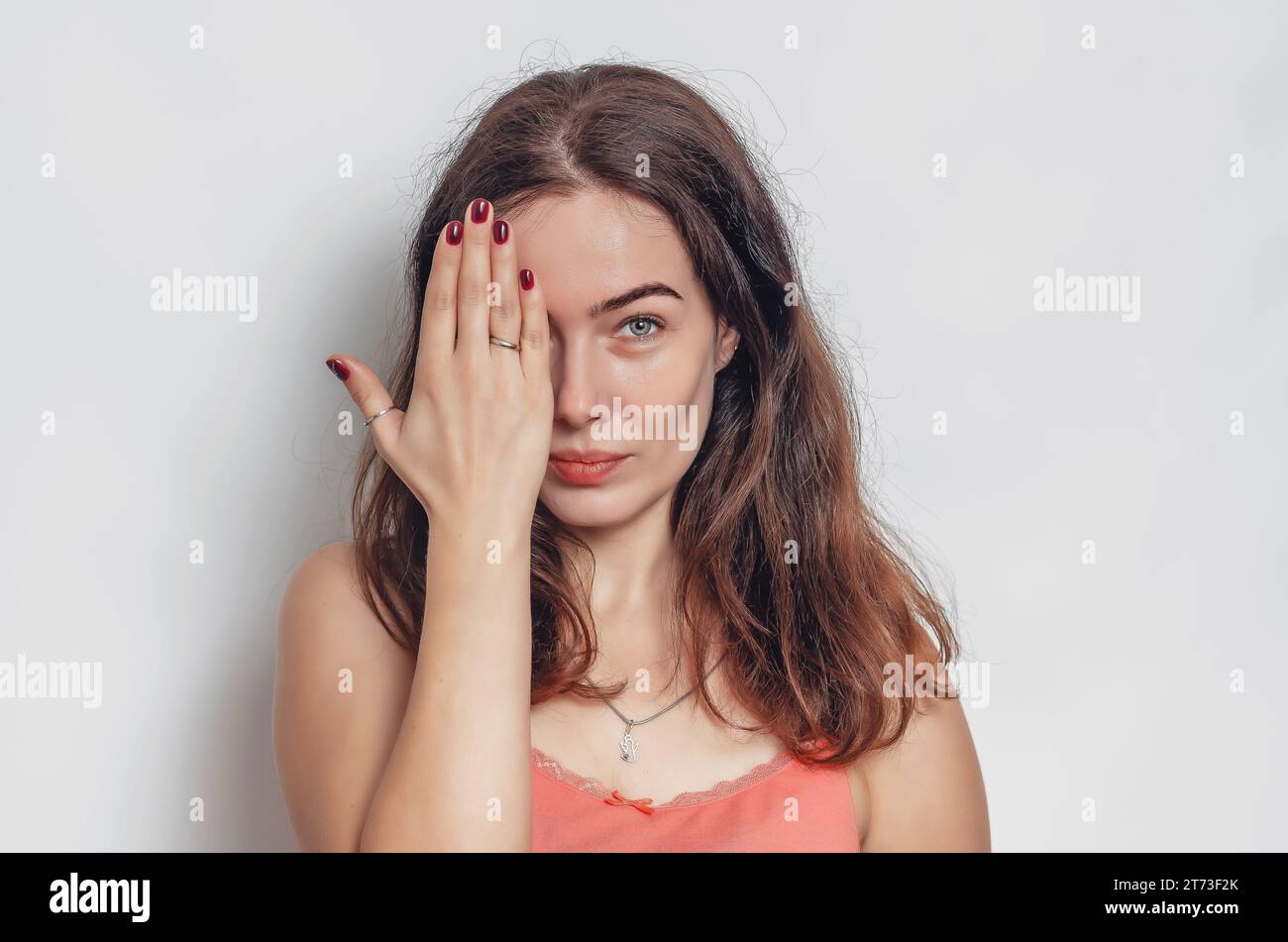 Cute woman with black hair covers her eye witr hand. Face close-up. Stock Photo
