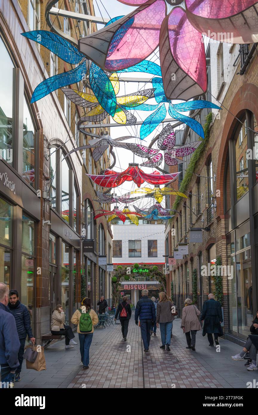 People walking in Slingsby Place, a pedestrian street in Covent Garden. Colourful overhead decorations. London, England, UK Stock Photo