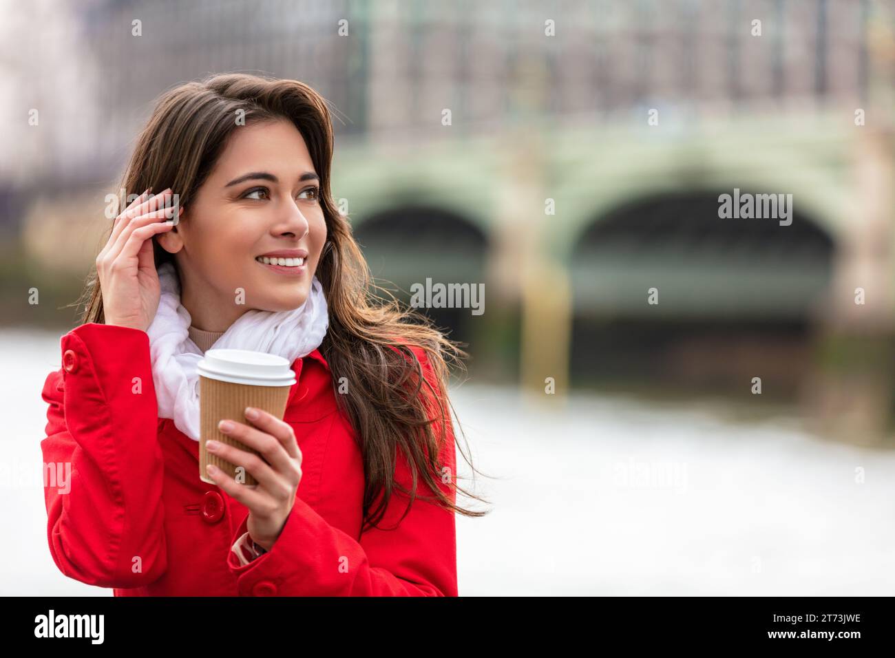 Girl or young woman drinking coffee in a disposable cup by Westminster Bridge in the background, London, England, Great Britain Stock Photo