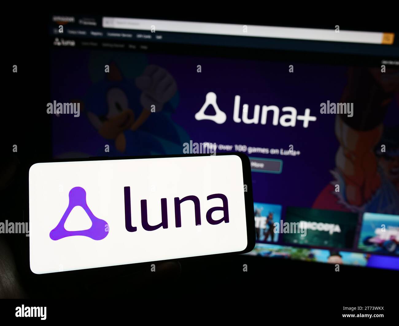 Person holding mobile phone with logo of American cloud gaming platform Amazon Luna in front of company web page. Focus on phone display. Stock Photo