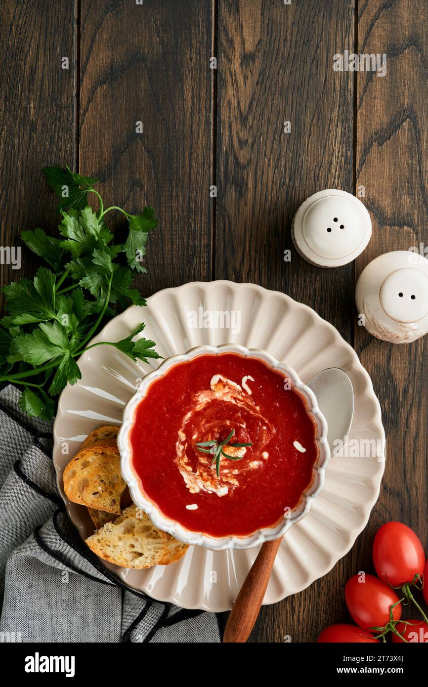 Soup. Tomato cream soup or gazpacho with herbs, seasonings, cherry tomato and parsley in white bowl on dark wooden old background. Healthy vegetable s Stock Photo
