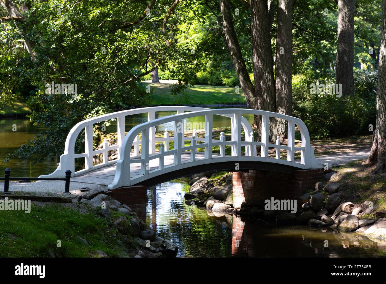 A little romantic bridge in a city park made of wood, painted in white. Park in natural light, on a sunny summer day. Stock Photo