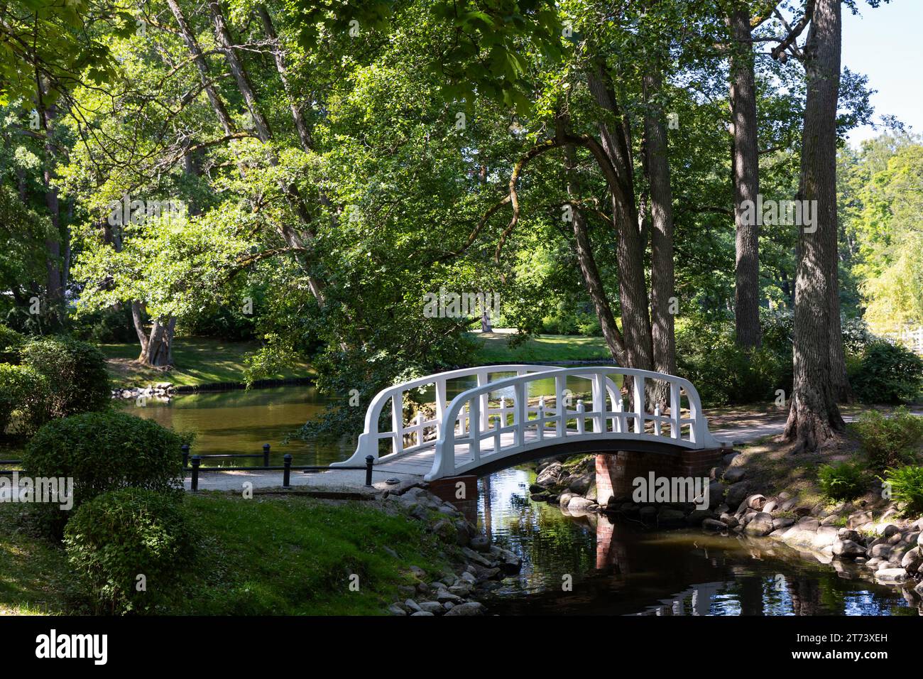 A little romantic bridge in a city park made of wood, painted in white. Park in natural light, on a sunny summer day. Stock Photo