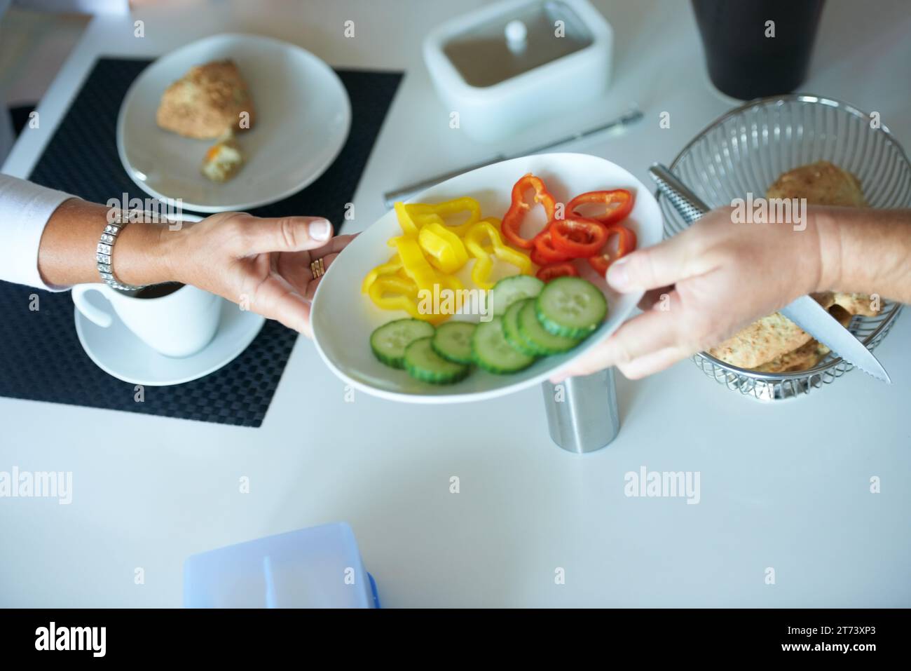 People, hands and passing salad at breakfast table for vegetables, diet or healthy eating at home. Closeup of person giving plate of natural organic Stock Photo