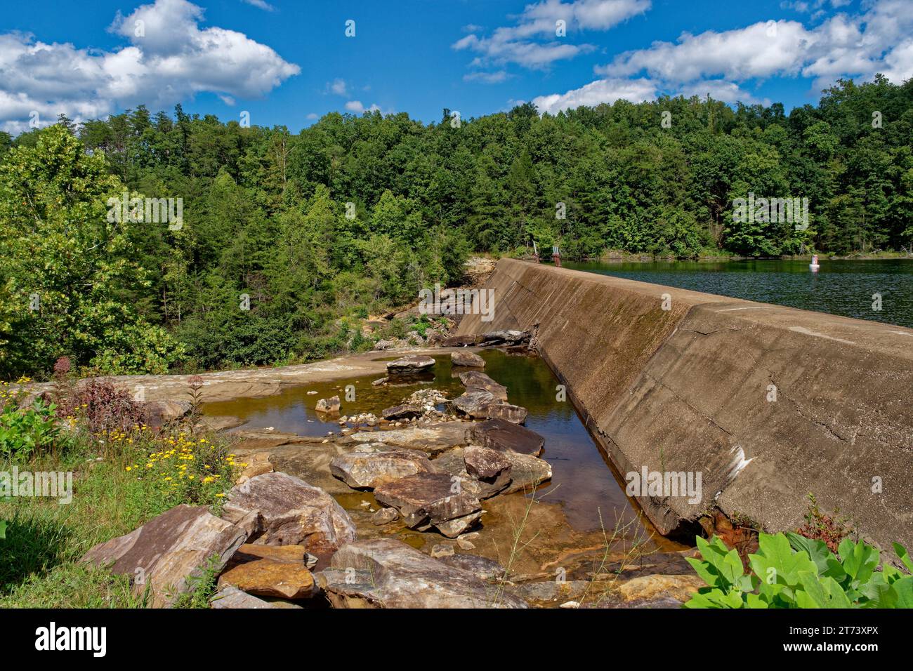 A dam at a lake with a cement wall separating the water levels at meadow creek park in Monterey Tennessee on a bright sunny day in early autumn Stock Photo