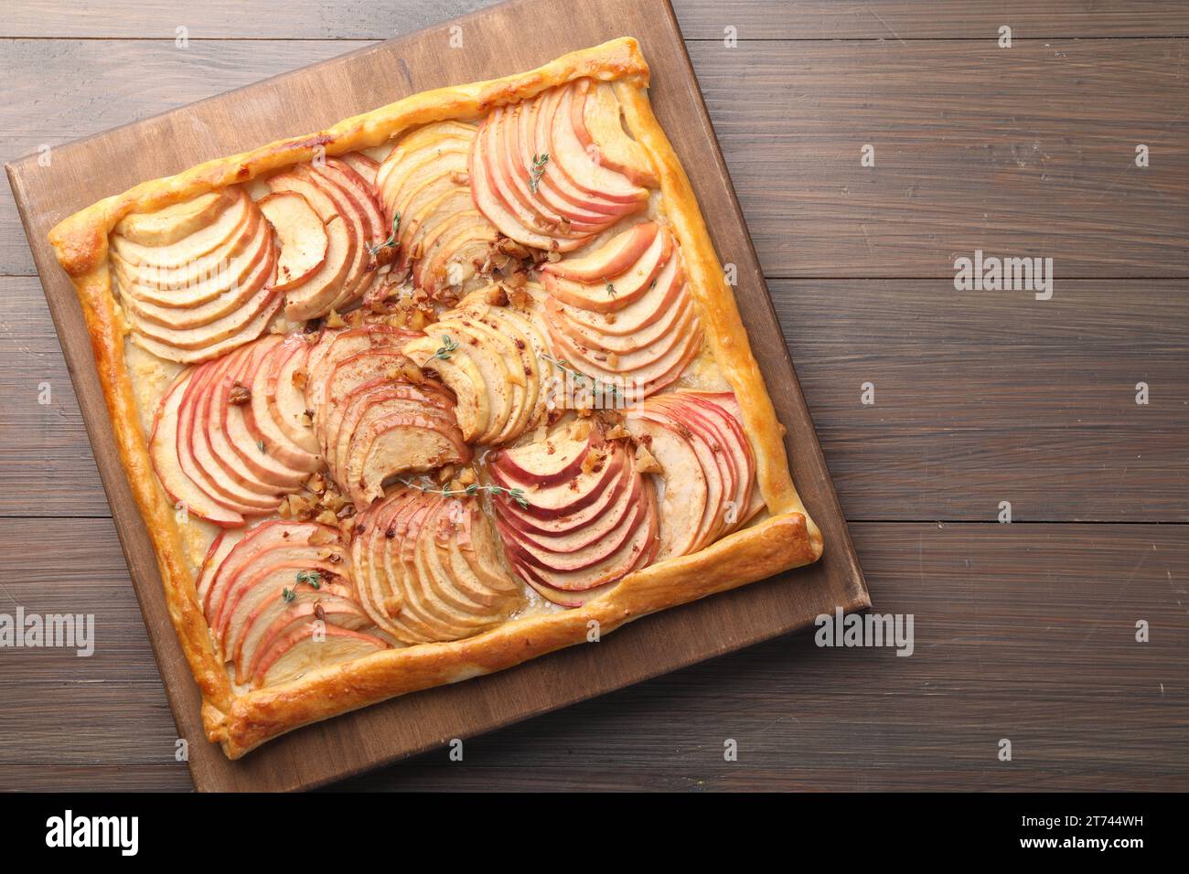Freshly baked apple pie with nuts on wooden table, top view Stock Photo