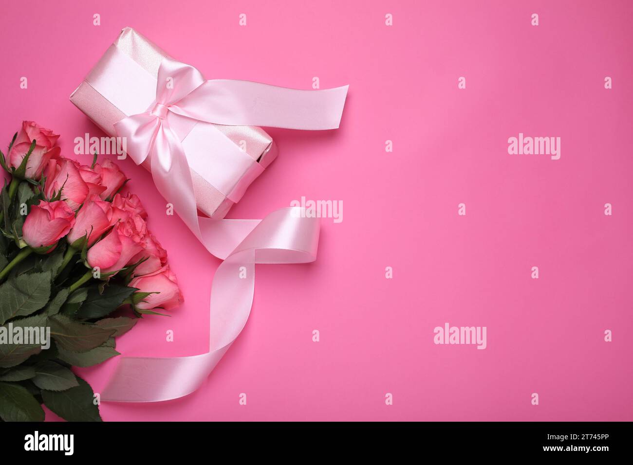 Beautiful gift box with bow and roses on pink background, flat lay ...