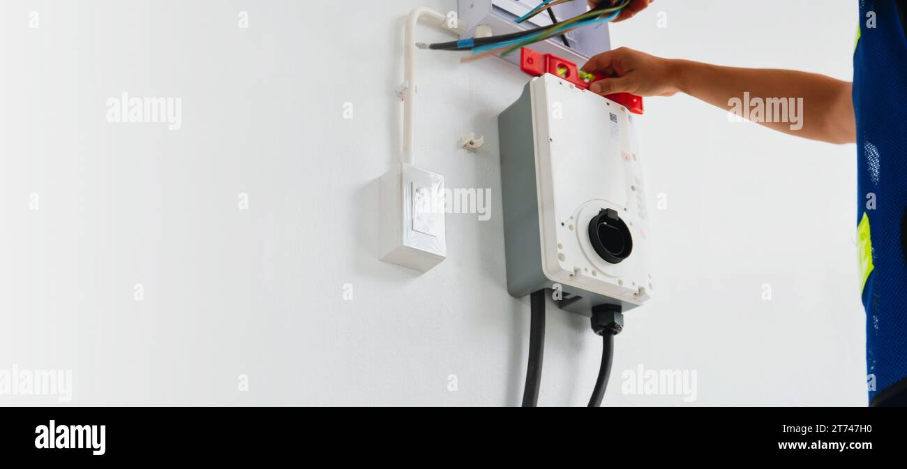 Certified male Electrician Installing Home EV Charger Stock Photo