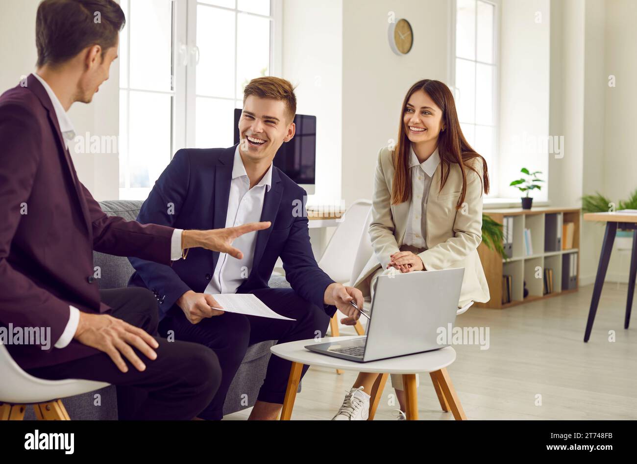 Three young business people at work in office talking and having ...