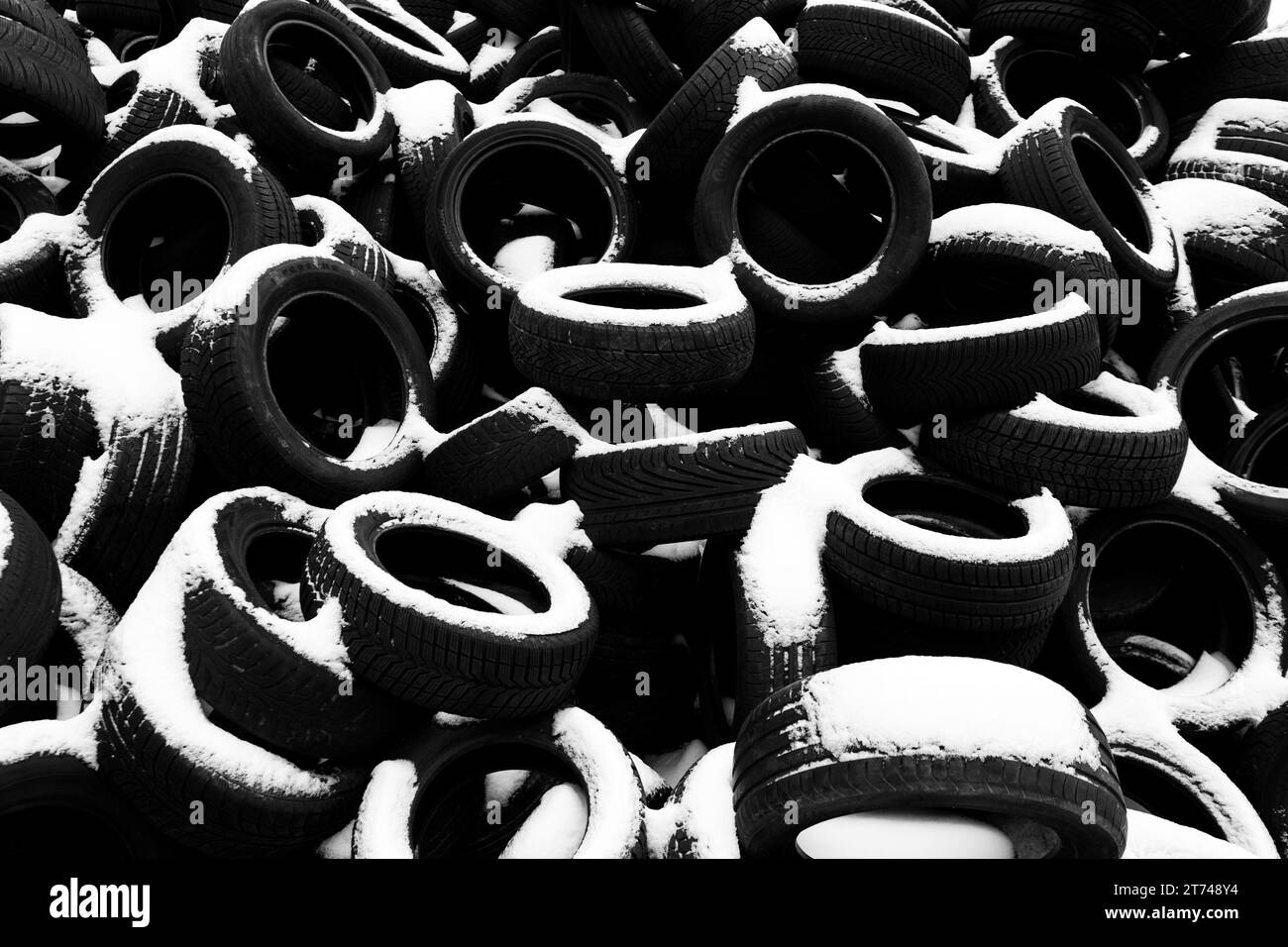 Pile of old tyres covered by snow. Black and white photography. Stock Photo