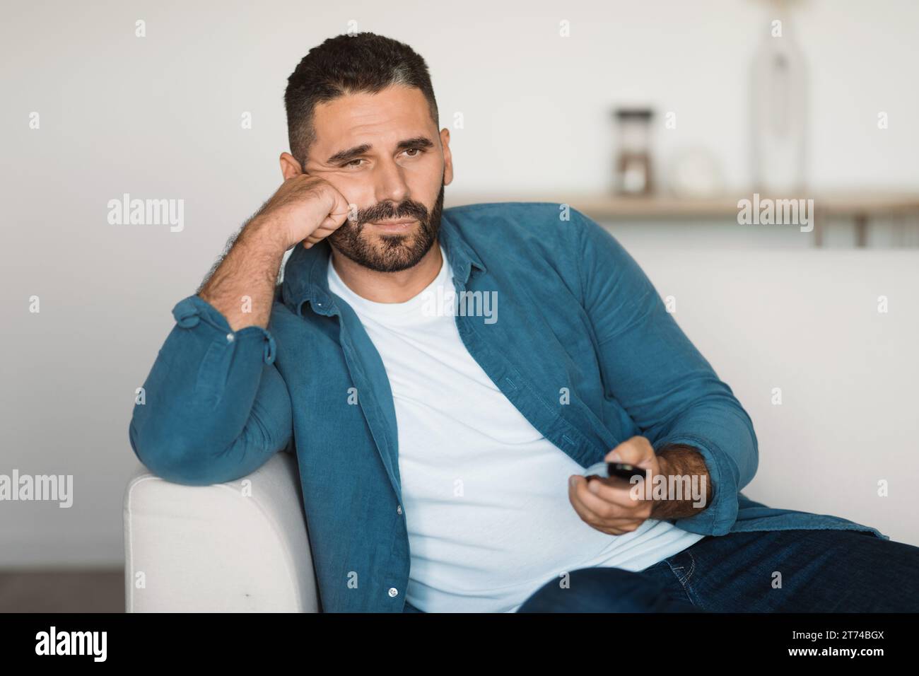 Man watching TV switching channels sitting at home Stock Photo