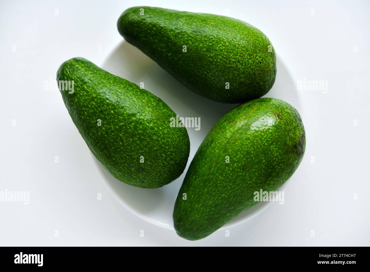 Ripe juicy avocado fruit on a white background. Vegetarian vegetables. Green fruits. Stock Photo