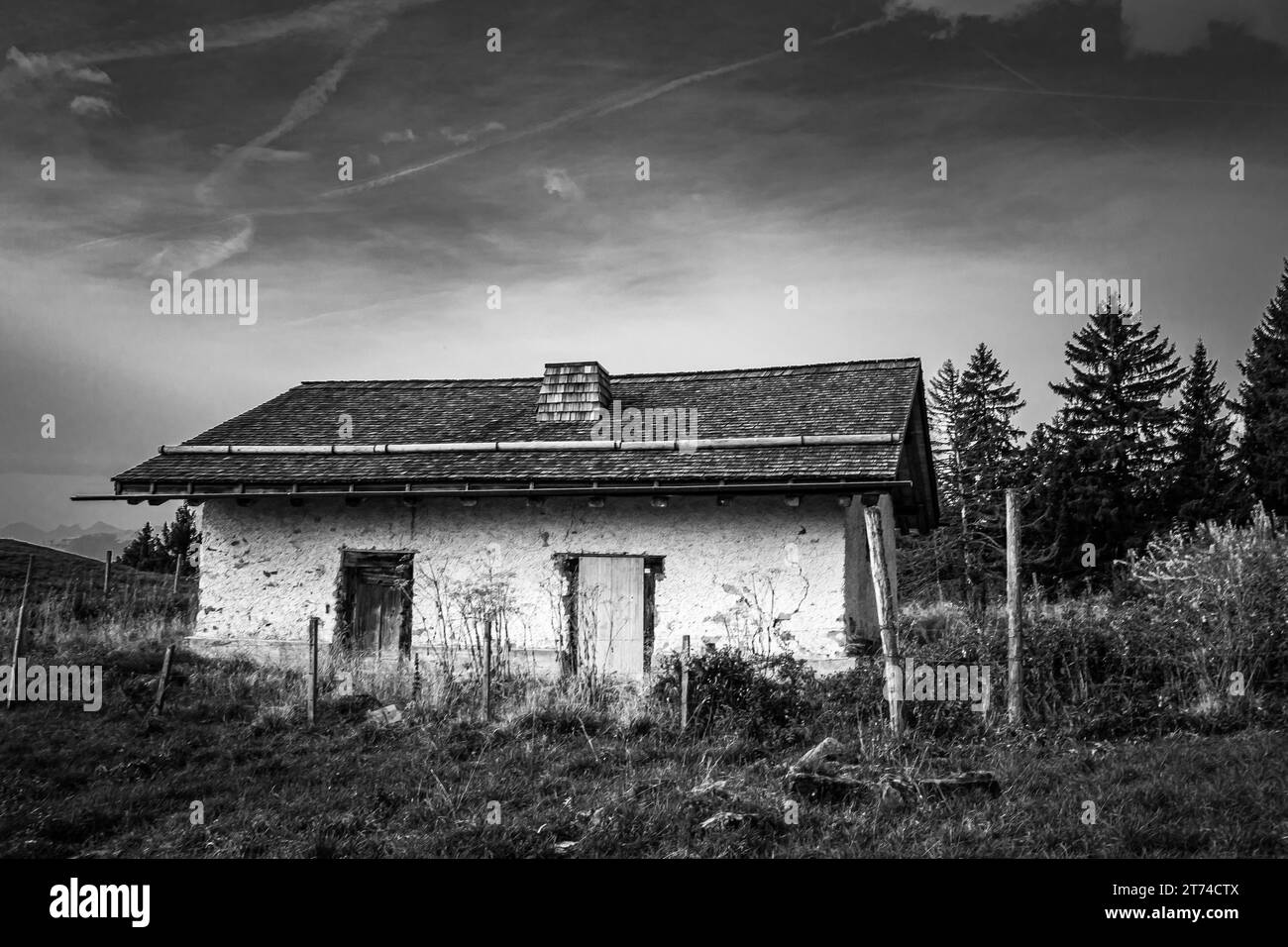 Black and white photograph of a rustic old house situated in a rural landscape Stock Photo