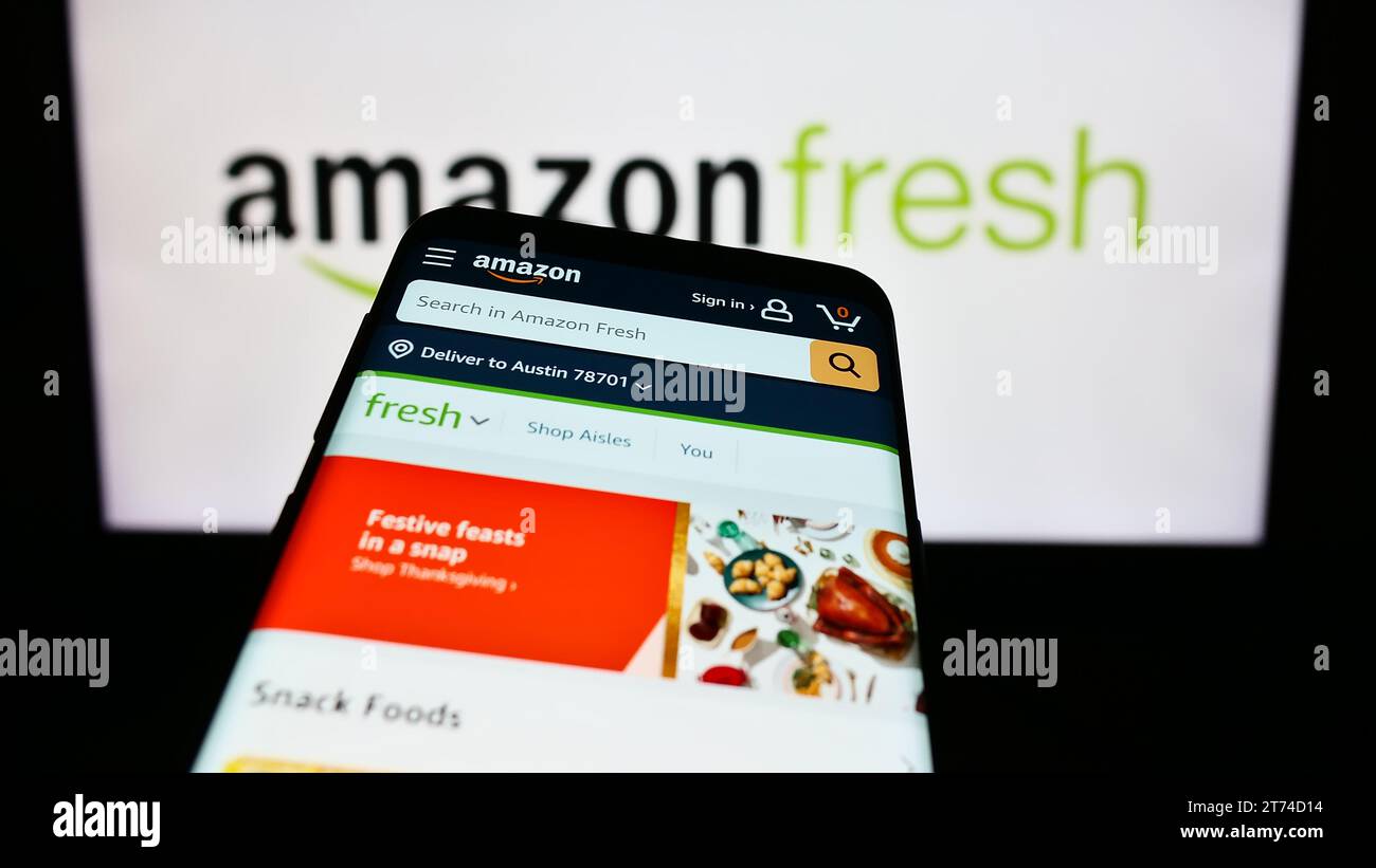 Mobile phone with website of US grocery retail company Amazon Fresh in front of business logo. Focus on top-left of phone display. Stock Photo