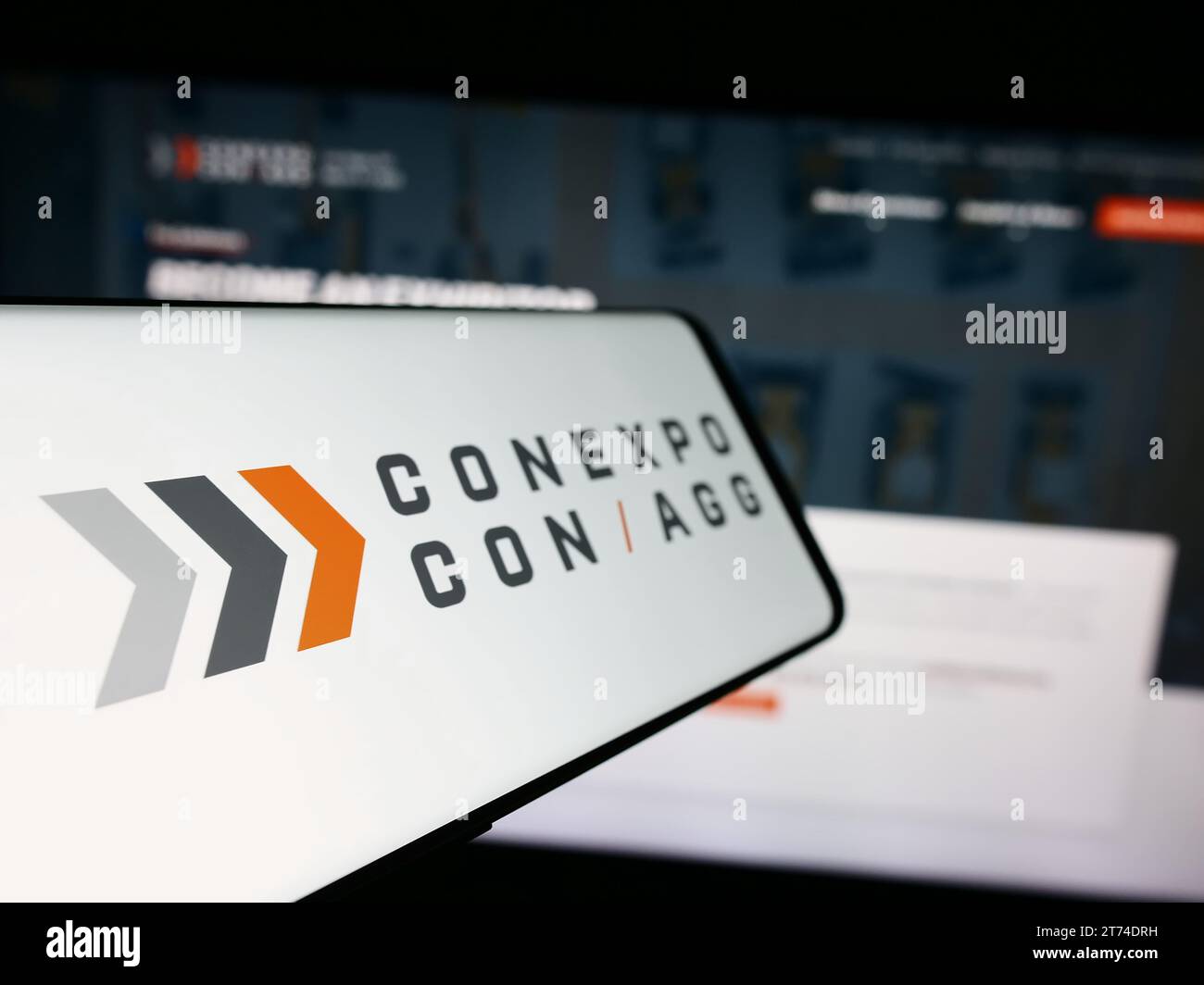Smartphone with logo of American construction trade show CONEXPO-CON-AGG in front of business website. Focus on center-left of phone display. Stock Photo