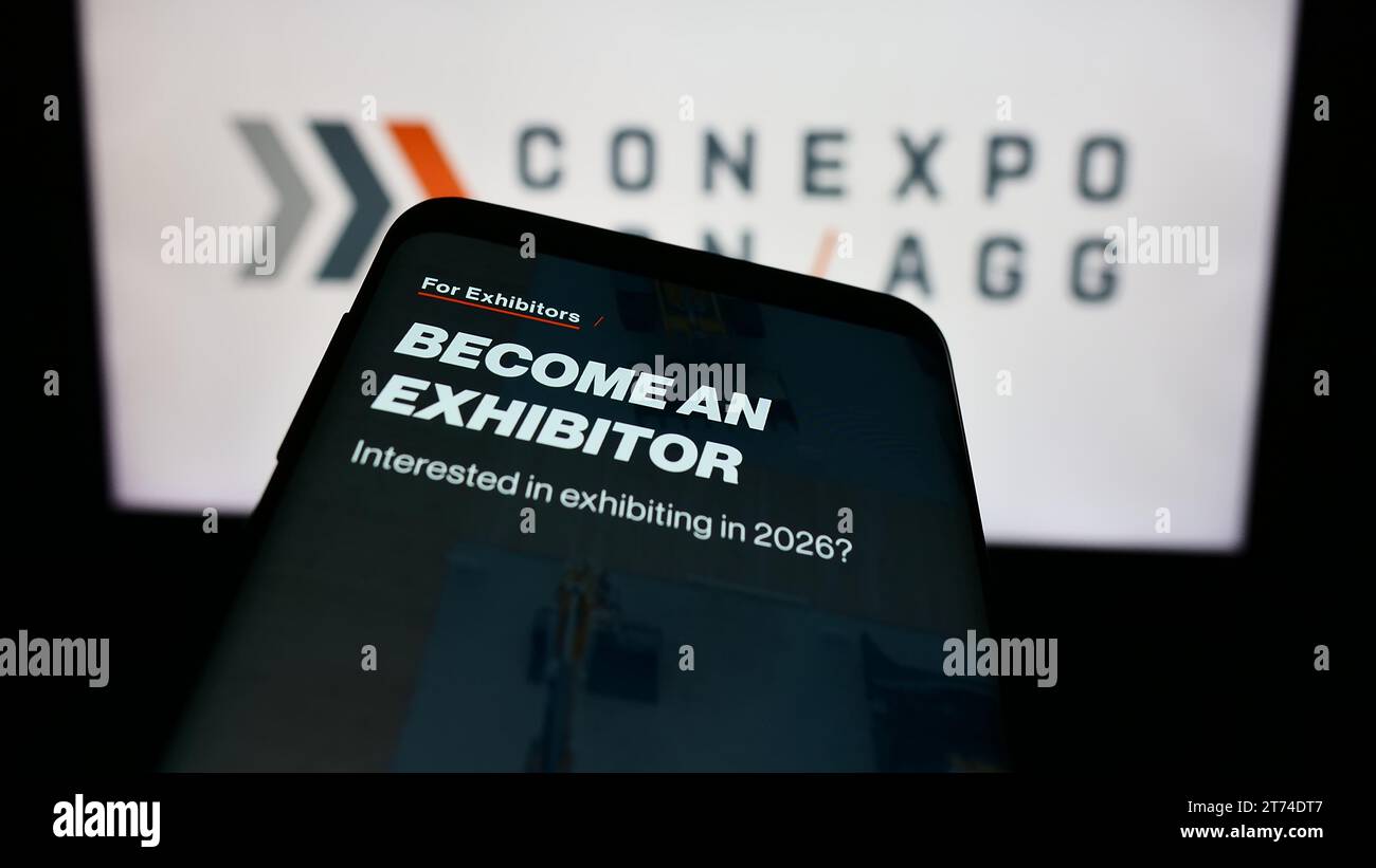 Mobile phone with website of US construction trade show CONEXPO-CON-AGG in front of business logo. Focus on top-left of phone display. Stock Photo