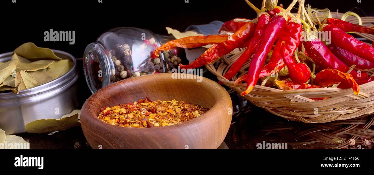 Wooden bowl of chili flakes, spices, bay leaf, red chili peppers still