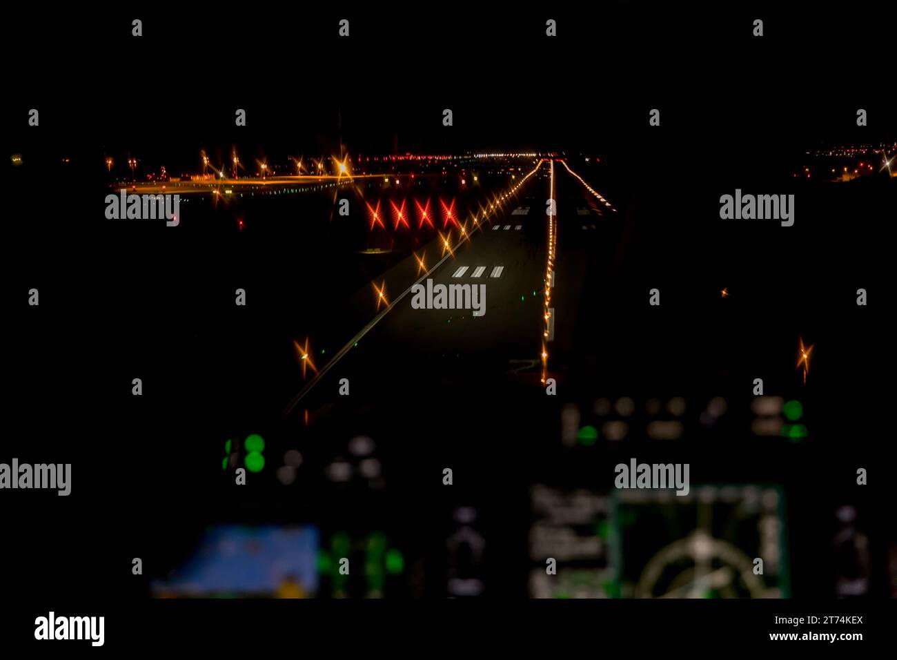 View from the cockpit of a modern airplane landing at an illuminated airport at night. Illuminated glass cockpit dashboard while landing at an airport Stock Photo