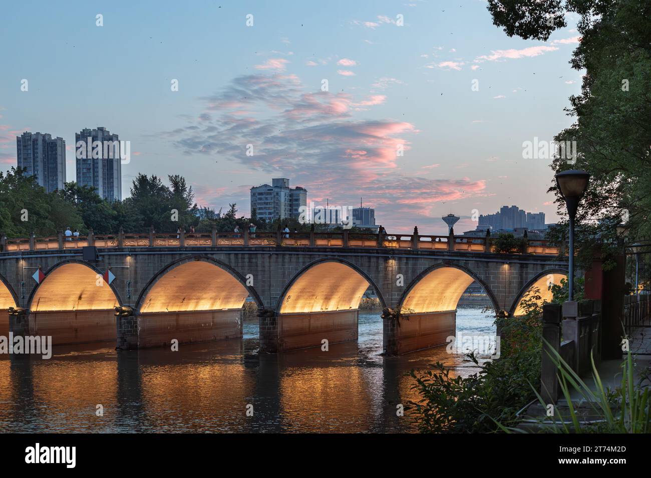 A stunning view of an arched bridge illuminated by a golden sunset Stock Photo